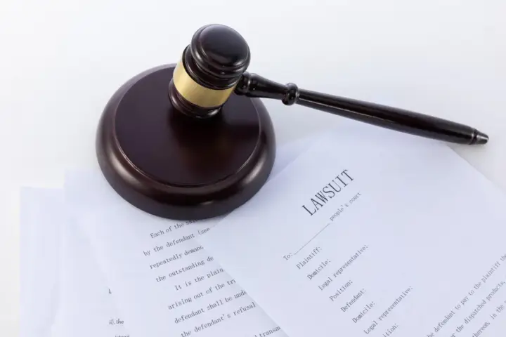 Młotek sędziowski na dokumentach sądowych, w tym na formularzu "LAWSUIT". Może posłużyć jako wzór wniosku o alimenty bez rozwodu.